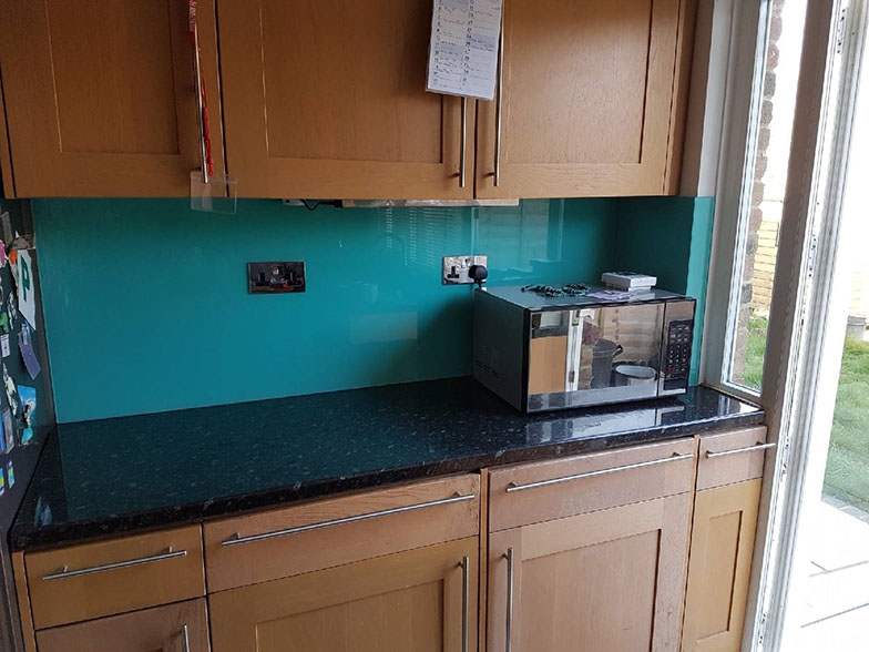 Teal back-painted glass splashback along a wooden kitchen run